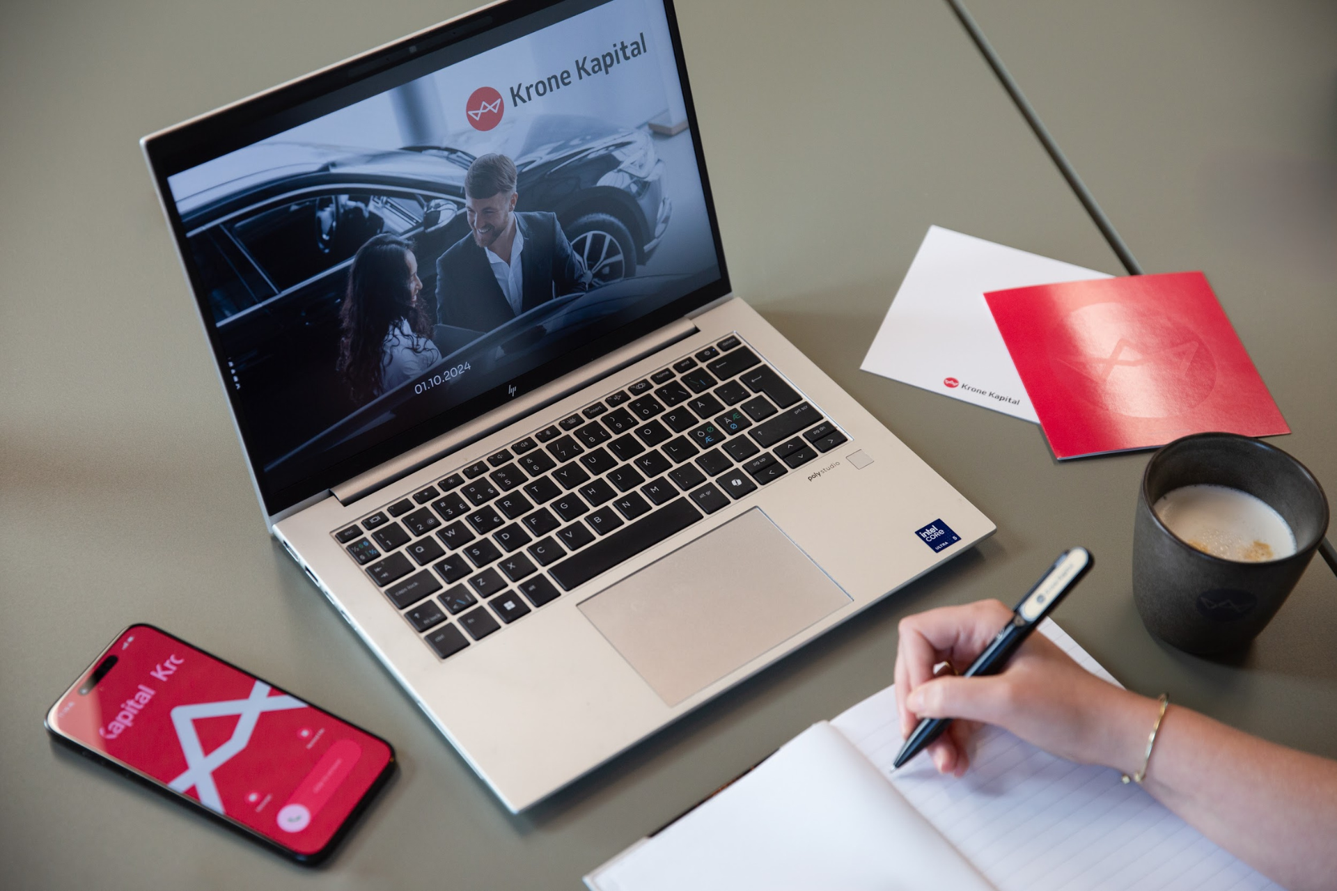 Skrivebord med Krone Kapital på PowerPoint slides, på telefonen og på kort ved siden af computeren. Uden vandmærke.