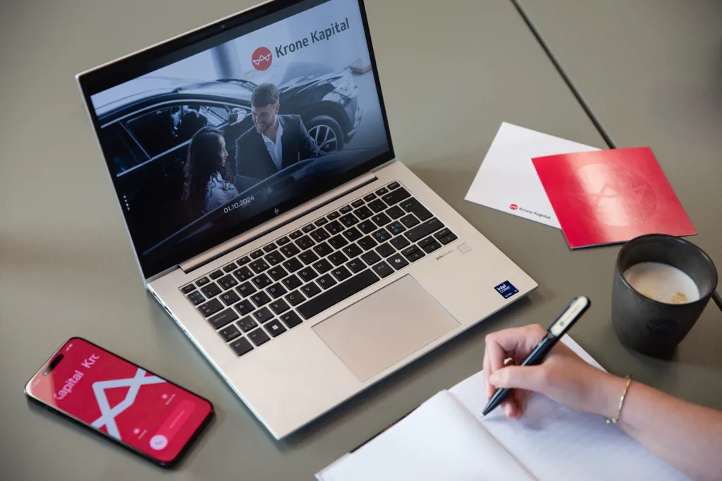Skrivebord med Krone Kapital på PowerPoint slides, på telefonen og på kort ved siden af computeren. Uden vandmærke.