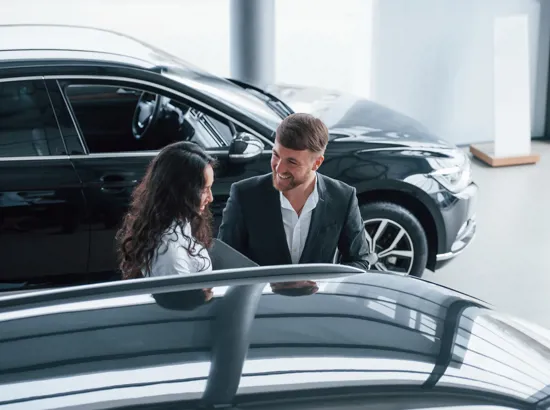 En mand og en kvinde står og kigger på ny bil ved en bilforhandler