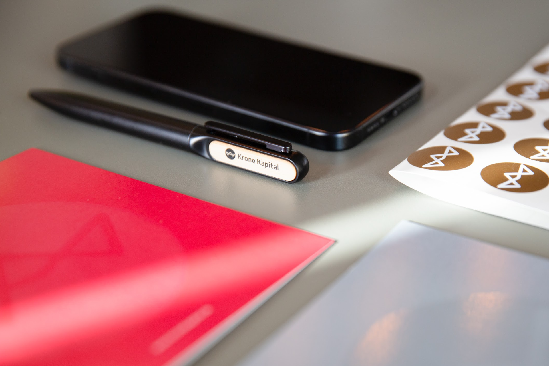 Et close up af Krone Kapital merchandise, der ligger på et skrivebord. Uden vandmærke.