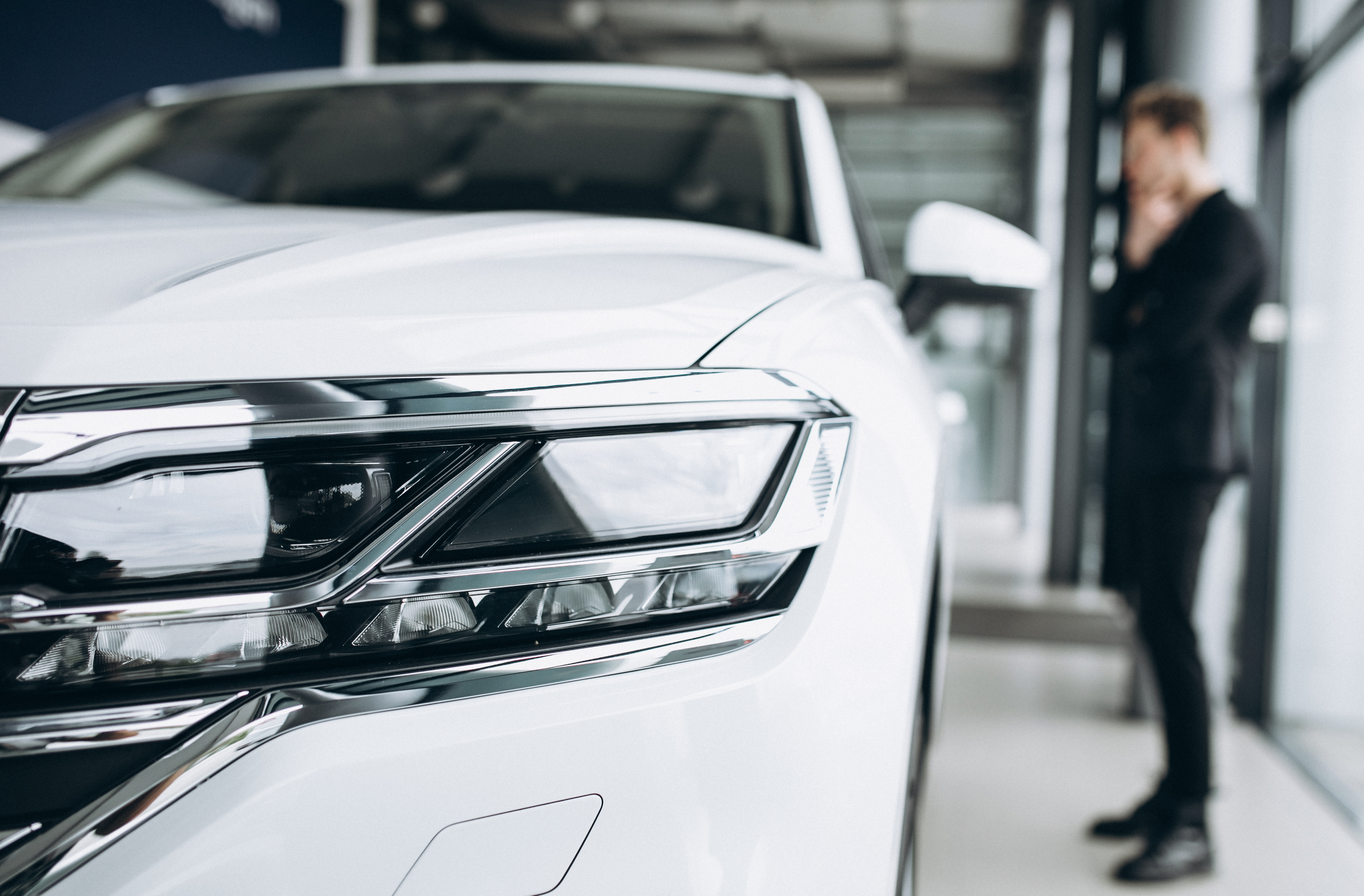 En mand står og kigger på en ny hvid leasingbil