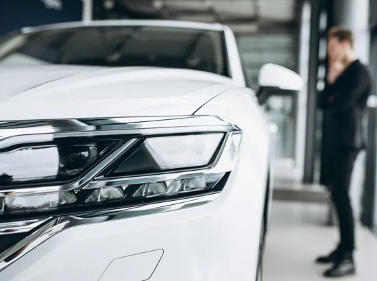 En mand står og kigger på en ny hvid leasingbil