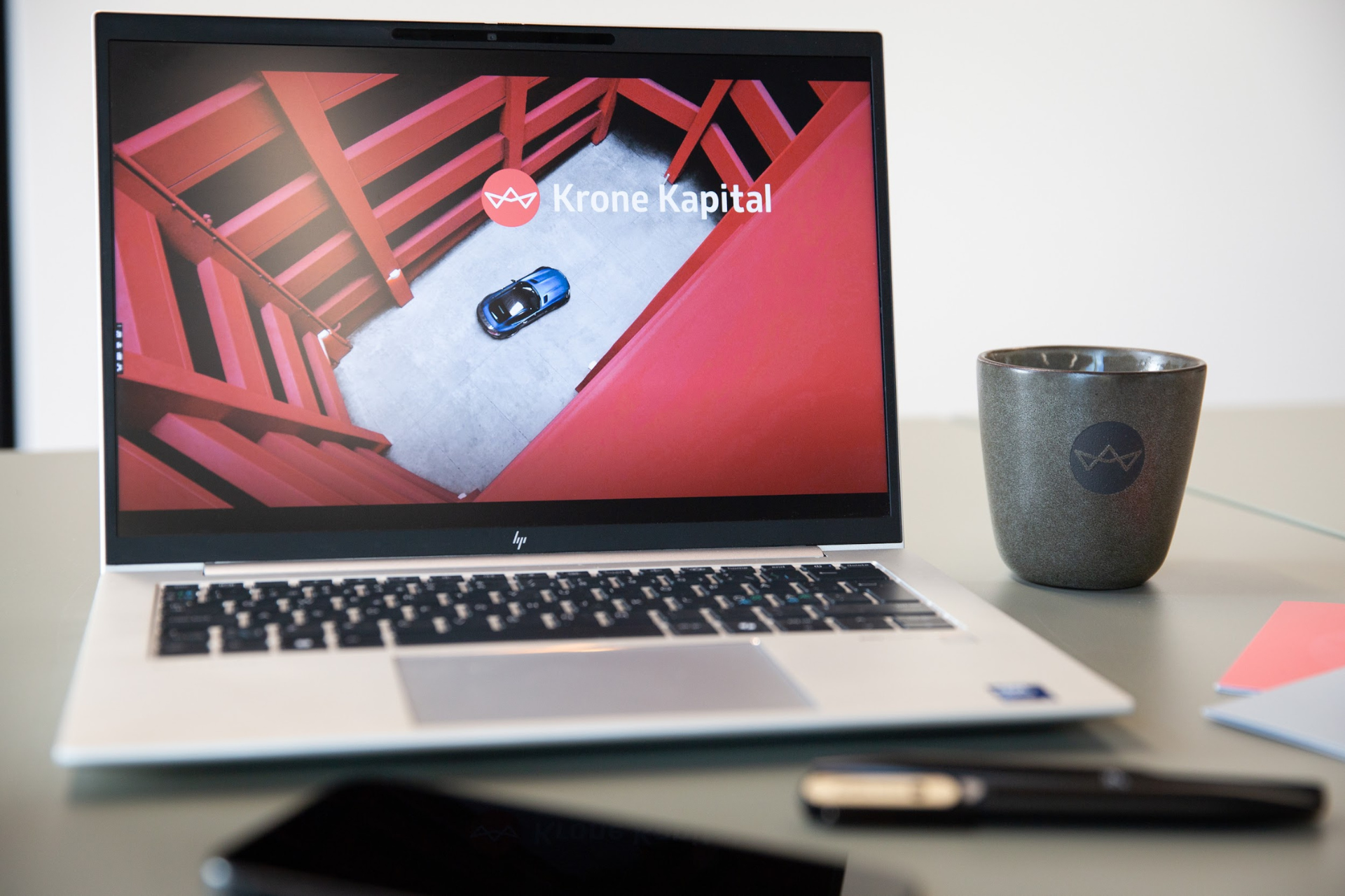 Billede af skrivebord med computer med Krone Kapital præsentation og Krone Kapital kaffekrus. Uden vandmærke.