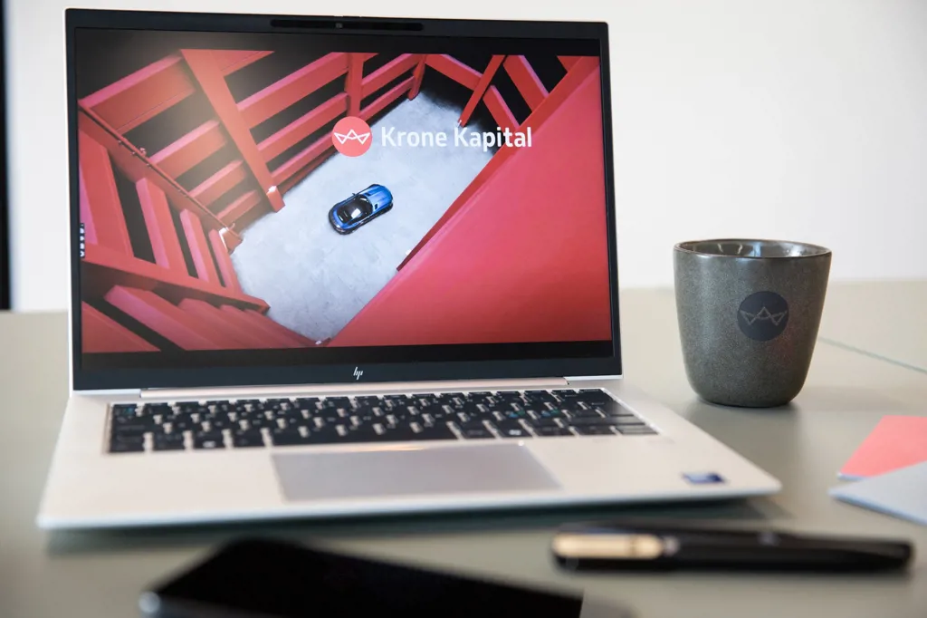 Billede af skrivebord med computer med Krone Kapital præsentation og Krone Kapital kaffekrus. Uden vandmærke.