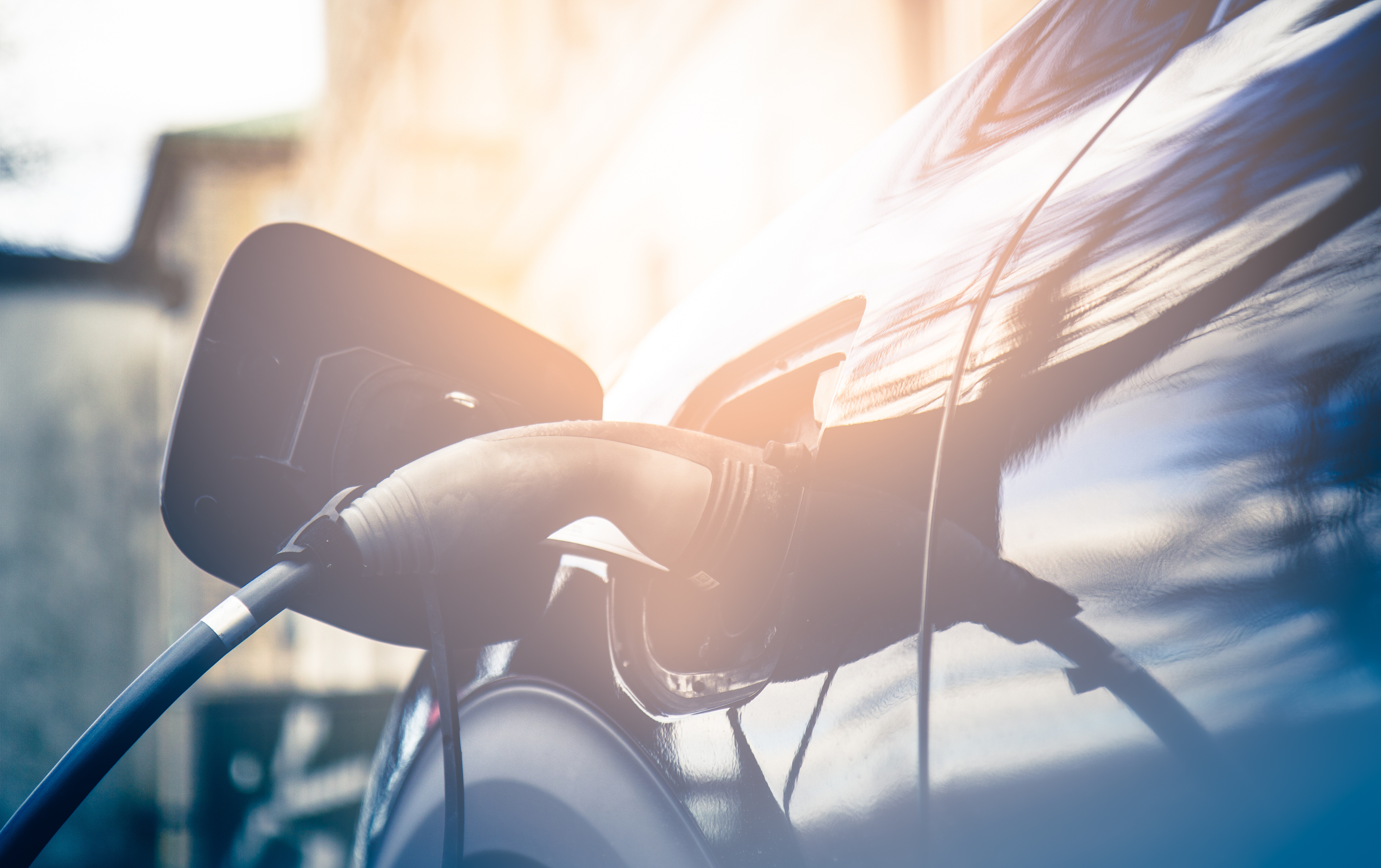 Blå elbil lader op mens det sidste af dagens solstråler ramme den. 