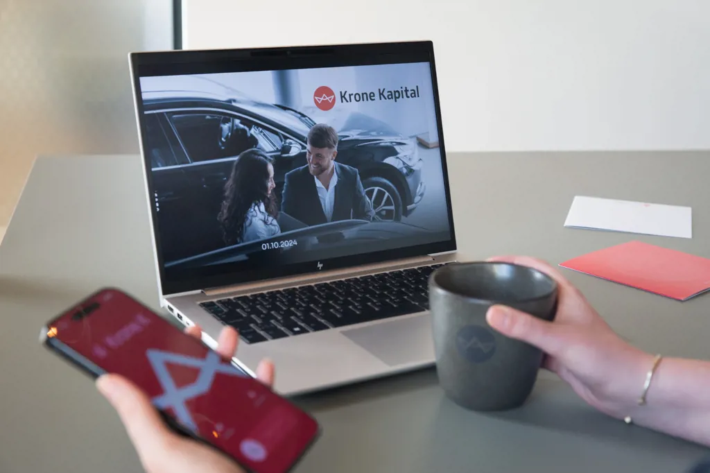 Kollega holder en kaffekop med Krone Kapital logo samt en telefon med et opkald fra Krone Kapital. Uden vandmærke.