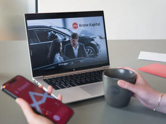 Kollega holder en kaffekop med Krone Kapital logo samt en telefon med et opkald fra Krone Kapital. Uden vandmærke.