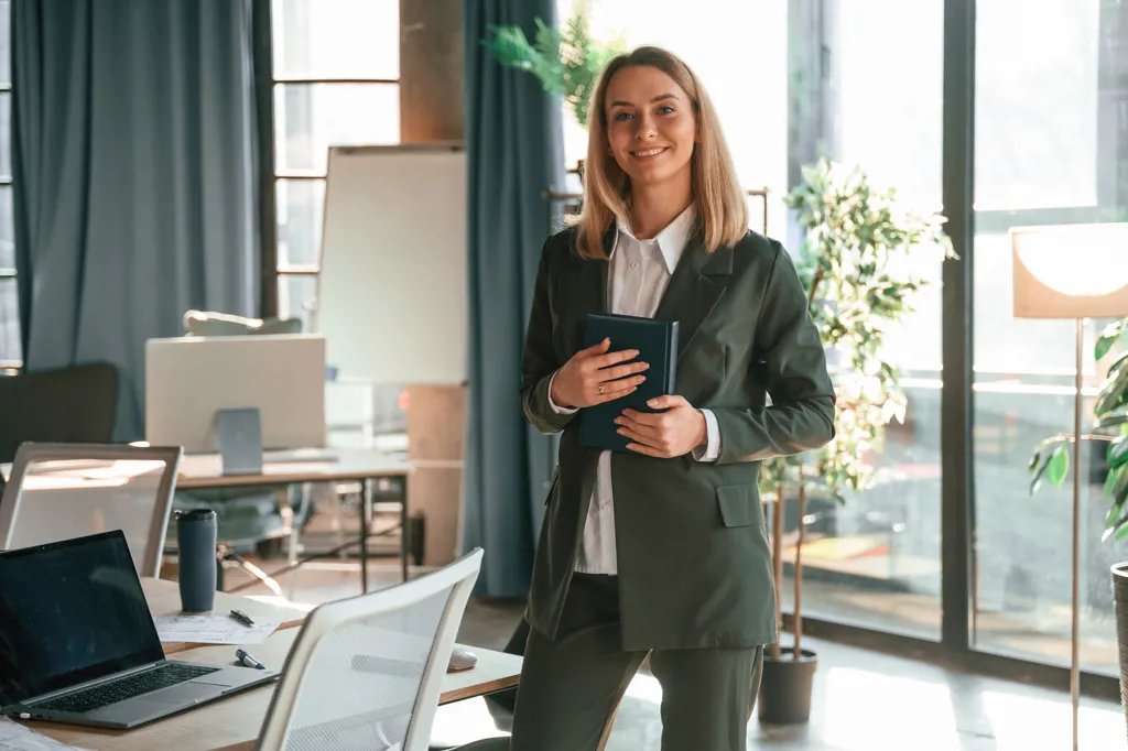 En kvinde står på kontoret med sin kalender i hænderne.