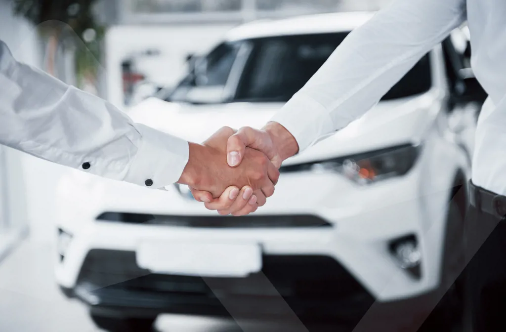 To personer der giver hinanden hånden med en varebil i baggrunden.