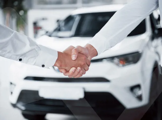 To personer der giver hinanden hånden med en varebil i baggrunden.